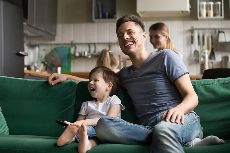 dad and his son on couch laughing