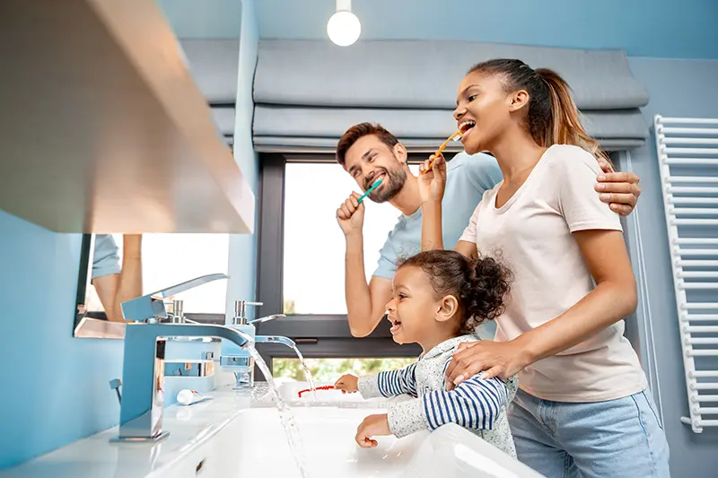 Mother, father and daughter brushing teeth in bathroom mother father and child brushing teeth at a sink