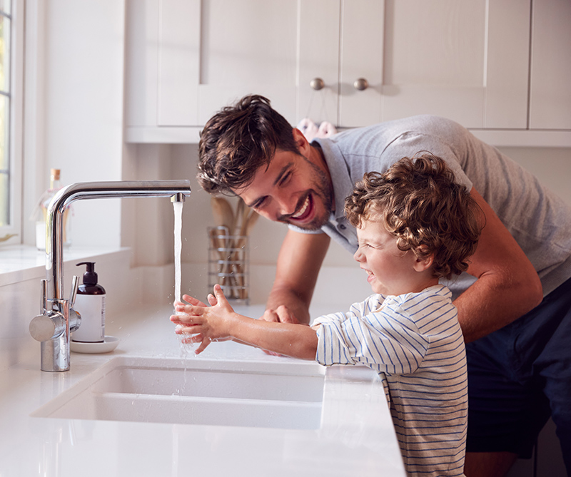father and son washing hands at sink