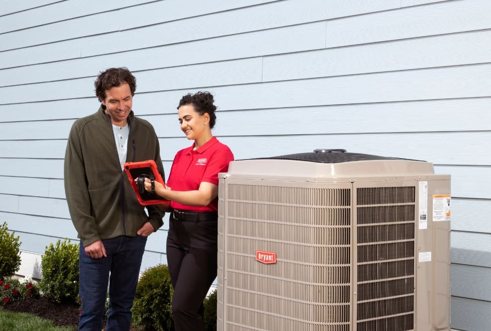 HVAC technician explaining AC capacitor replacement to a homeowner outside their house, discussing AC repair options, air conditioner not starting, capacitor issues, and safe DIY vs. professional HVAC service with Lochard HVAC, Plumbing, and Service. Trust us to help you with replace AC capacitor, how to replace AC capacitor, AC capacitor replacement cost, bad AC capacitor symptoms, air conditioner not turning on, AC not cooling, AC capacitor troubleshooting, HVAC capacitor issues, DIY AC capacitor replacement, AC repair near me, HVAC repair near me, air conditioner repair near me, HVAC services near me, emergency AC repair, professional AC repair, Lochard HVAC services, HVAC technician near me, air conditioning repair services, residential AC repair, AC maintenance near me, central AC capacitor replacement, HVAC parts replacement, air conditioner won’t start, home AC not blowing cold air, AC capacitor blown, capacitor replacement for HVAC system, licensed HVAC company near me, Piqua HVAC repair, Troy AC service, Sidney HVAC technician.