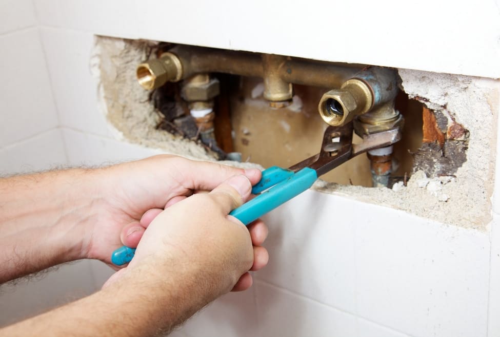 Plumber fixing a shower leak behind a wall with a wrench, Lochard HVAC, Plumbing, and Service leak detection, hidden water leak repair, pipe repair, plumbing services, emergency plumbing, and professional water damage prevention. Reach out today for help with plumber detect leaks behind walls, hidden water leak detection, wall leak repair, leak detection services near me, plumbing leak detection near me, water leak repair near me, emergency plumbing leak repair, slab leak detection, ceiling leak repair, shower leak behind wall repair, pipe leak detection, water line leak repair, plumbing repair services near me, professional leak detection, home water leak services, leaking pipe repair, bathroom leak repair near me, kitchen leak detection, leak repair services, Lochard HVAC Plumbing and Service plumbing repair, HVAC plumbing services near me, pipe repair services near me.